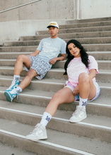 Load image into Gallery viewer, Our models sitting on the stairs featuring our girl model wearing and representing MG Lifestyle Summer Tees (Pink) combined with our Pastel Bandana Shorts and MadGrind socks then our boy model wearing and representing our MG Lifestyle Summer Tees (Baby Blue) combined with Die or MG Hoop Shorts, MadGrind socks and MadGrind Curved Visor Snapback Hat.